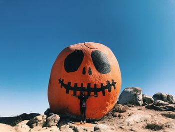 Close-up of pumpkin on rock against clear blue sky