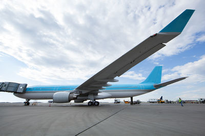 Low angle view of airplane parked runway against sky