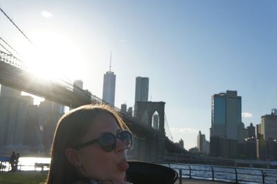 Portrait of young woman in city against sky