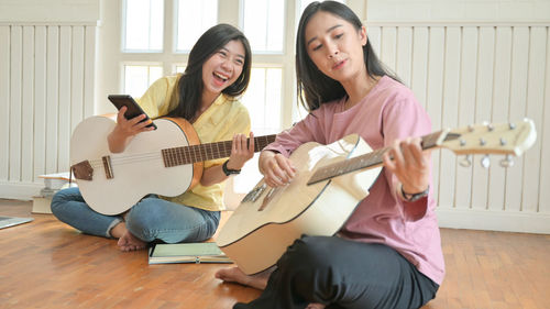 Young woman playing guitar at home