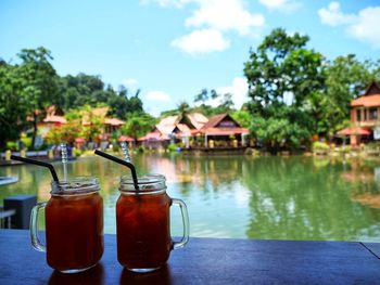 View of drink on table by swimming pool against sky