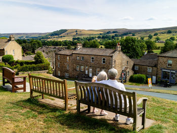 Rear view of people sitting outside building against sky