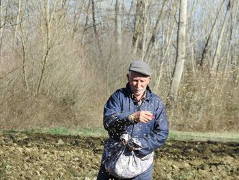 Senior man spreading seeds in farm