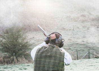 Rear view of man shooting with rifle