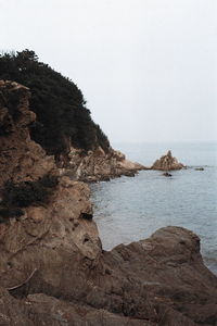 Rock formations on shore against clear sky