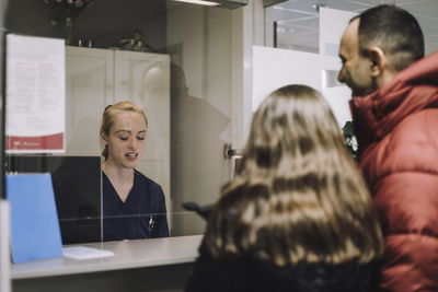 Female receptionist discussing with patient at healthcare center