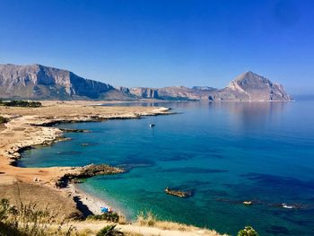 Panoramic view of sea and mountains against clear blue sky