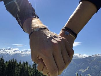 Couple holding hands on mountain against sky