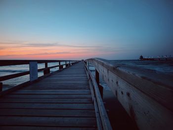 Pier over sea against sky during sunset