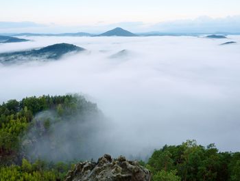 Scenic view of misty mountains against moody sky