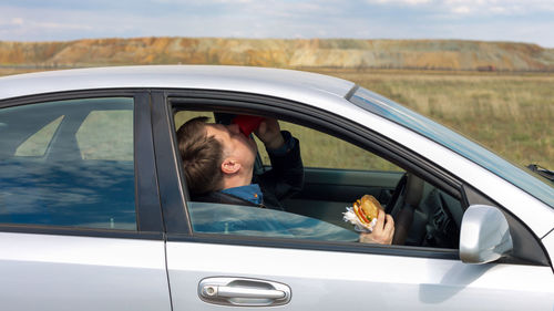 The manager eats lunch at wheel in the car.