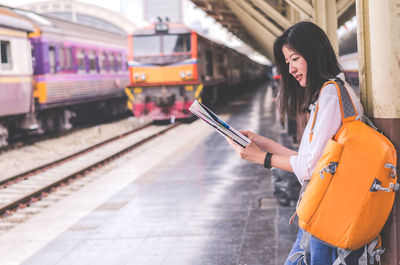 Rear view of woman using mobile phone at railroad station