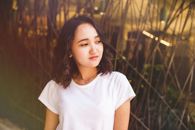 Young asian woman in a white t-shirt calm looking at the side. street portrait, lifestyle concept