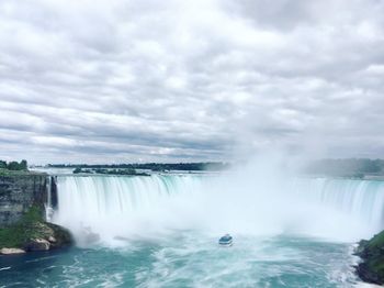 View of waterfall against cloudy sky