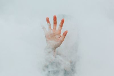 Hand of person amidst white smoke