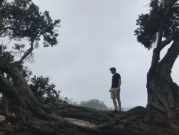 Man standing on rock against sky