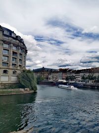 Buildings by river against sky in city