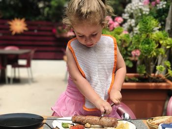 Girl cutting sausage while having food at restaurant