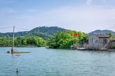 Scenic view of lake by trees and buildings against sky