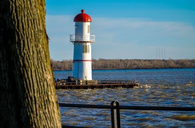 Lighthouse by sea against sky