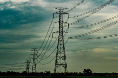 Low angle view of silhouette electricity pylon against sky