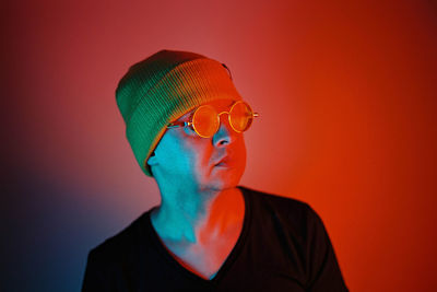 Close-up portrait of young man against orange wall