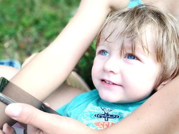 Midsection of mother holding boy and mobile phone at park