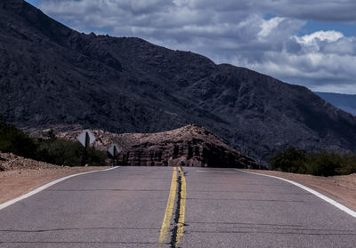 Road by mountains against sky