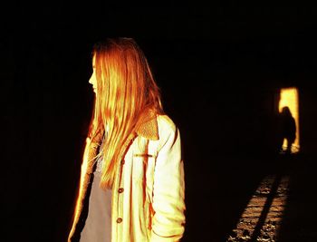 Rear view of woman standing against black background