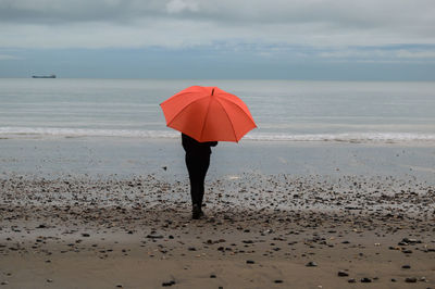 Woman standing on beach against sky