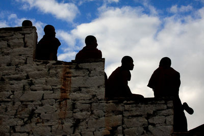 Low angle view of silhouette people standing against cloudy sky