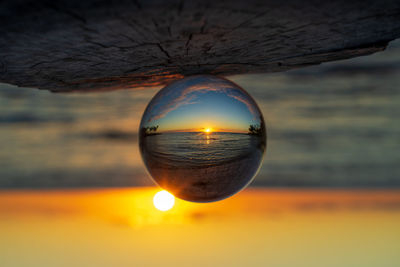 Close-up of crystal ball against sky during sunset