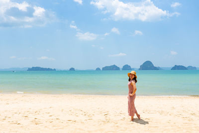 Asian woman dancing on the beach and looking at blue sea in sunny day during summer vacation