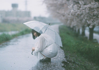 Woman holding umbrella walking on wet rainy season