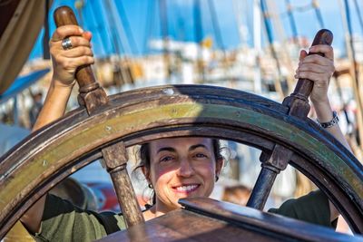 Portrait of smiling woman holding steering wheel on boat