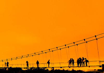 Low angle view of people walking against clear sky