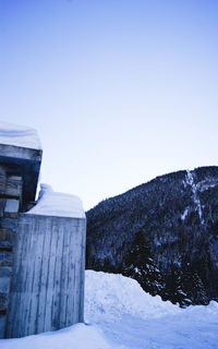 Snow covered landscape against clear blue sky