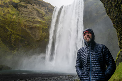 Smiling man feeling happy while visiting skogafoss waterfall in iceland