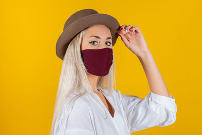 Portrait of woman wearing hat against yellow background