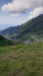 Scenic view of green landscape and mountains against sky