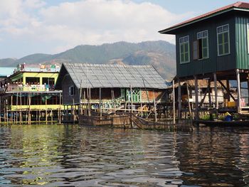 Houses by lake against sky