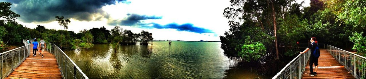 water, the way forward, sky, railing, boardwalk, pier, tranquility, tranquil scene, diminishing perspective, beauty in nature, nature, scenics, panoramic, cloud - sky, jetty, men, vanishing point, lake, tree