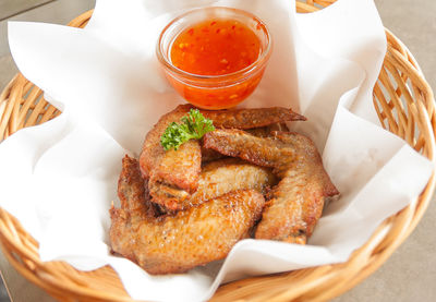 High angle view of fried chicken wings with sauce in basket