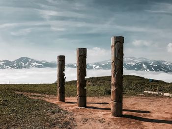 Wooden posts on field against sky