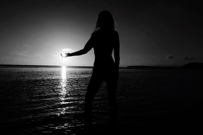 Silhouette woman standing in sea against sky