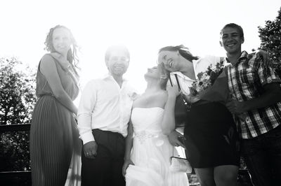 Newlywed couple with friends standing outdoors