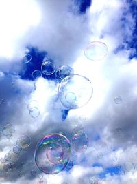 Low angle view of bubbles against blue sky