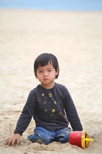 Portrait of cute girl sitting on sand at beach