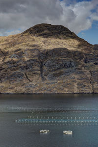 Mussel farming in lake amidst mountain against sky