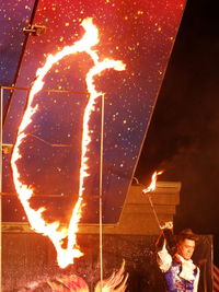 Reflection of woman in sky with fire in background at night